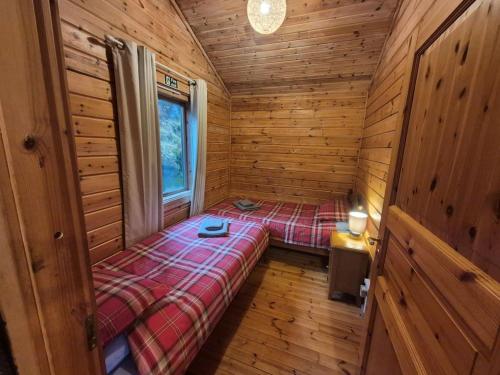 a small room with a bed in a wooden cabin at Eas Lodge in Tobermory