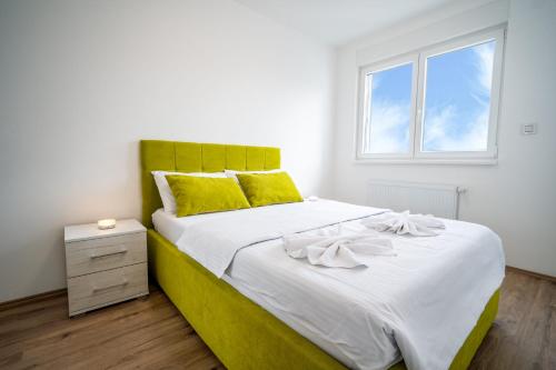 a bedroom with a large bed with a yellow headboard at Renome apartmani in Banja Koviljača
