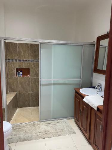 a bathroom with a shower and a toilet and a sink at Modern colonial house in Apastepeque