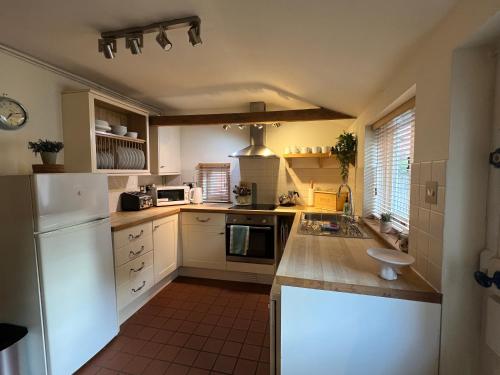 a kitchen with white cabinets and a white refrigerator at White Horse Cottage with Sauna in Ollerton