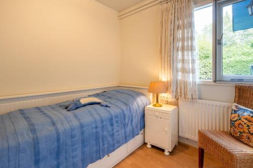 a bedroom with a blue bed and a window at BlauweBoshuis in Koekange