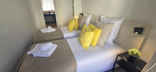 a bedroom with two beds with yellow and white pillows at Le Patio de l'Isle 2nd Duplex in Périgueux