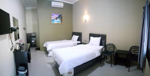 a hotel room with two beds and a table and chairs at Mata Ie Resort in Sabang
