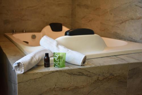 a bathroom with a tub and two towels and a bottle of beer at Pousada Viver Capitólio in Capitólio