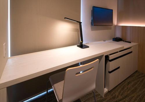 a desk in a hotel room with a lamp on it at JR Inn Sapporo-eki Minami-guchi in Sapporo
