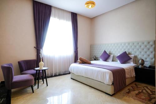 a bedroom with a bed and a chair and a window at Palais Dar Souhir in Aït Bou Zguia