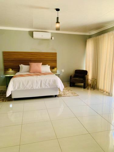 a large bedroom with a bed and a chair at The Botik Hides in Mogwase