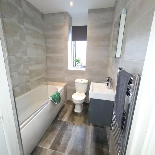 a bathroom with a tub and a toilet and a sink at Modern - City Centre - Free parking in Norwich
