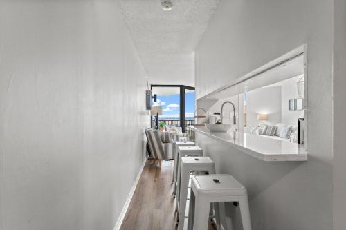 a bathroom with a row of white sinks and stools at Beachfront Condo With Beautiful Sunset in Panama City Beach