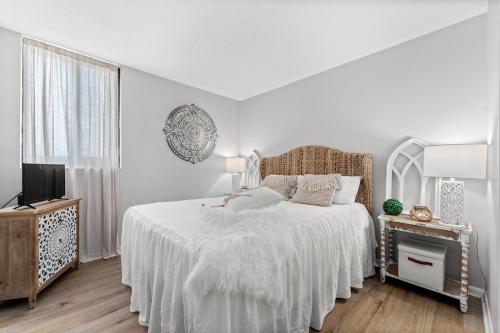a white bedroom with a bed and a television at Beachfront Condo With Beautiful Sunset in Panama City Beach