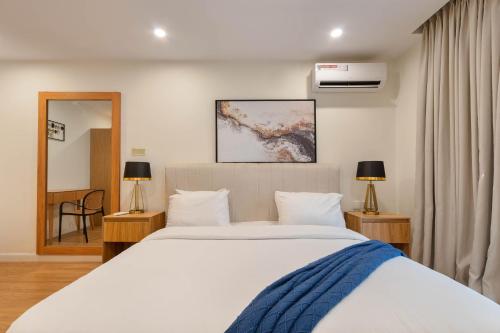 a bedroom with a large white bed and a mirror at Aima Apartments in Lagos
