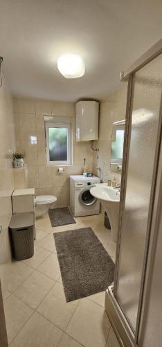 a bathroom with a sink and a washing machine at Inas Place in Baška Voda