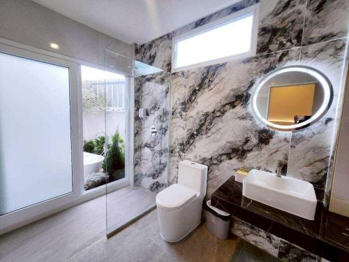 a bathroom with a toilet and a sink and a mirror at NY grand villa in Nong Prue