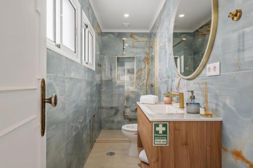 a bathroom with a toilet and a sink and a mirror at Villa Amor Do Mar -180° Sea View, Jacuzzi,Terrace in Funchal