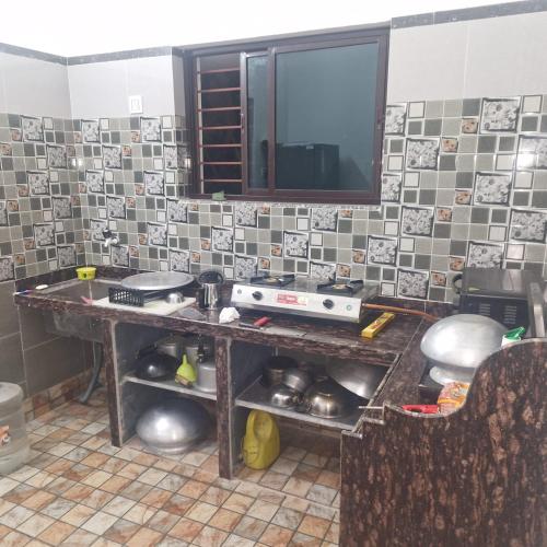 a kitchen with a table with a tv on the wall at shreejikunj in Bolpur