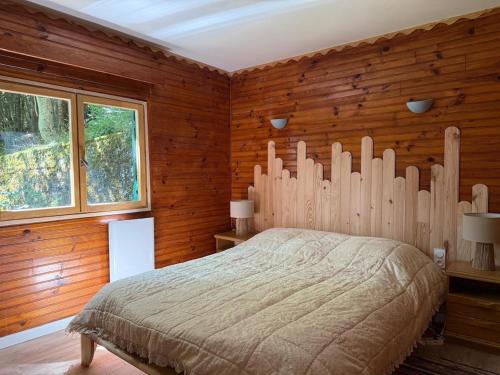a bedroom with a large bed with wooden walls at Lou Rigal in Dourbies