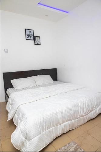 a bed with white sheets and two pictures on the wall at The 4 Kays Apartment - One Bedroom in Agege