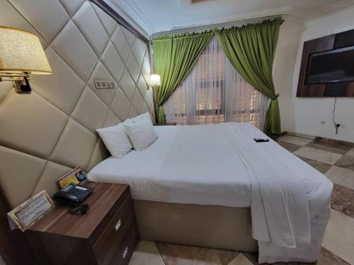 a bedroom with a bed and a table with a telephone at Valencia Hotels Abuja in Abuja