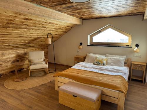 a bedroom with a bed and a chair and a window at Apartamenty Polna Ostoja in Tylicz