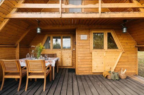 a wooden cabin with a table and chairs on a deck at Mała Toskania in Kawec