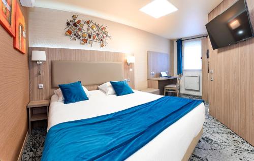 ein Hotelzimmer mit einem großen Bett und blauen Kissen in der Unterkunft The Originals City, Archotel, Sens in Sens