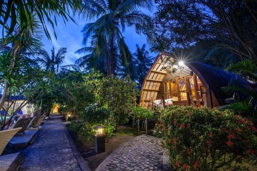 a resort with benches and trees and a building at Manta Dive Gili Trawangan Resort in Gili Trawangan