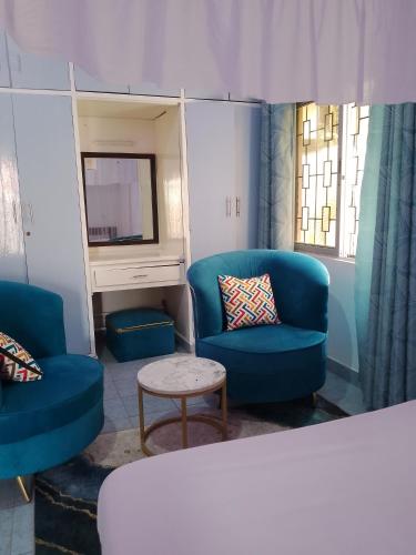 a living room with two blue chairs and a tv at Kamsons in Mombasa