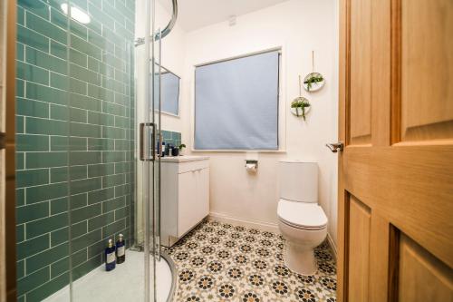 a bathroom with a toilet and a glass shower at Stylish 3 Bed House, Free Parking, Near M53, Fast WiFi, Garden in Ellesmere Port
