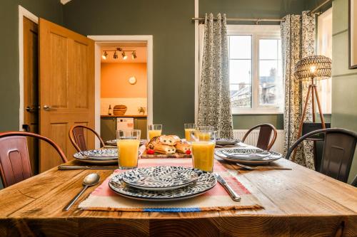 a dining room table with plates and glasses of orange juice at Stylish 3 Bed House, Free Parking, Near M53, Fast WiFi, Garden in Ellesmere Port