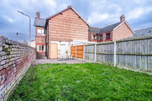 a brick house with a fence and a yard at Stylish 3 Bed House, Free Parking, Near M53, Fast WiFi, Garden in Ellesmere Port
