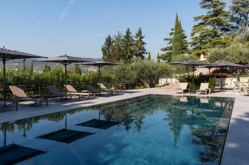 a swimming pool with lounge chairs and umbrellas at Villa Bocchi by Geco Vacation Rentals in Negrar