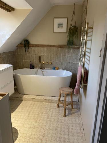 a white bath tub in a bathroom with a stool at Thatch Cottage Singleton 2 miles from Goodwood in Singleton