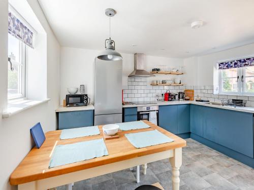 a kitchen with blue cabinets and a wooden table at The Pink Cottage in Bottisham