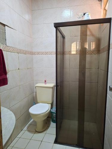 a bathroom with a toilet and a glass shower door at Hostel Repou-Z in Goiânia