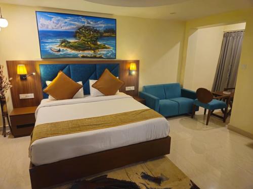 a bedroom with a large bed and a blue chair at Aither in Digha
