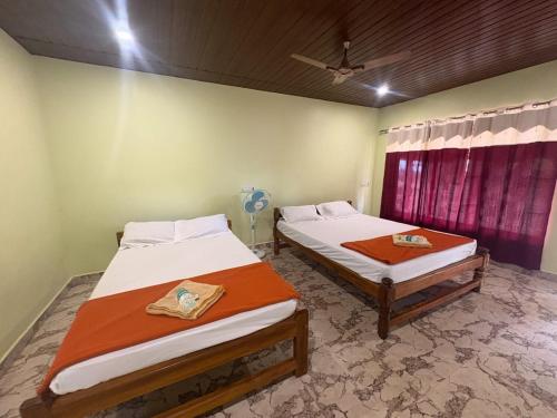 a bedroom with two beds and a window at Coco Beach Front Stay & Cafe in Gokarna