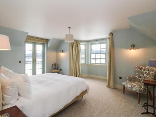 a bedroom with a large white bed and windows at Schiehallion House in Pitlochry