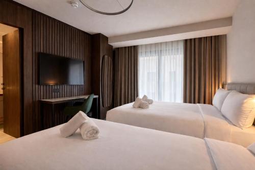 ein Hotelzimmer mit zwei Betten und einem Flachbildfernseher in der Unterkunft ASTE hotel in St Julian's