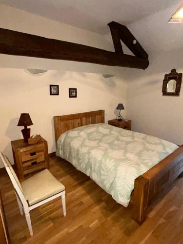 a bedroom with a large bed and a chair at La Ferme de Francois in Saudron