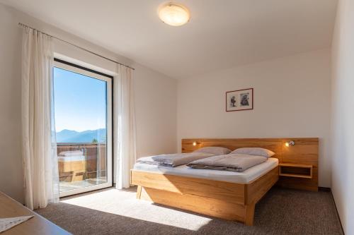 a bedroom with a bed and a large window at Pension Rastnerhof in Luson