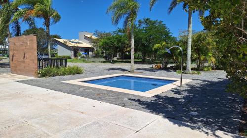 a swimming pool in a yard with palm trees at Casa de hospedes em condominio com lazer in Búzios