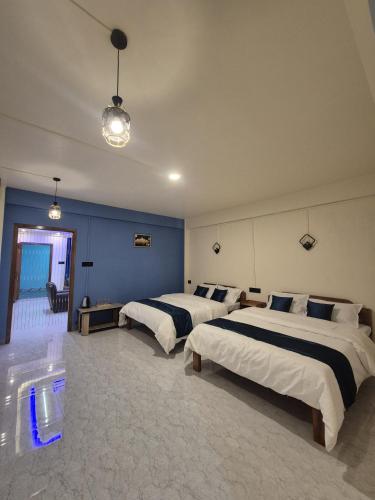 a bedroom with two beds and a blue wall at Eyana Residency in Lāitlyngkot