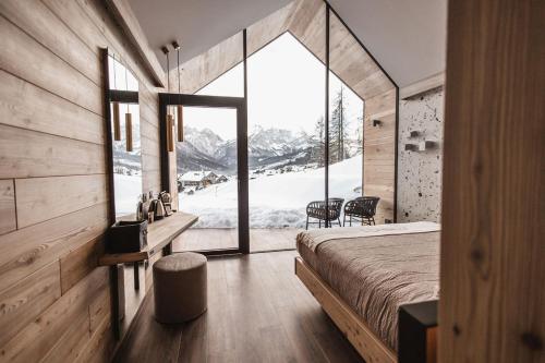 a bedroom with a bed and a large window at Borgo Antico Mountain Lodge in Sappada