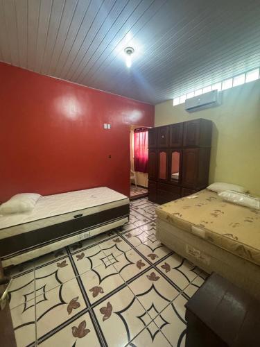 two beds in a room with a red wall at Casa Altos JM in Ananindeua