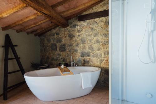 a bath tub in a bathroom with a stone wall at Fattoria San Donato in San Gimignano