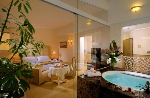 a bathroom with a tub and a living room at Hotel De Londres in Rimini