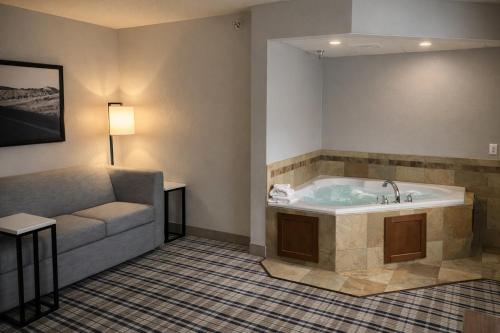 a hotel room with a tub and a couch at AmericInn by Wyndham Dickinson in Dickinson