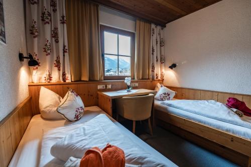 a room with two beds and a desk and a window at Liebes Caroline 4-Sterne-Hotel in Pertisau