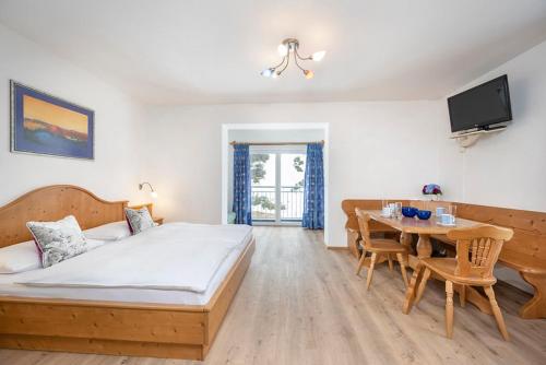 a bedroom with a bed and a table and a television at MIA Appartements - non-serviced Appartements in Obertauern