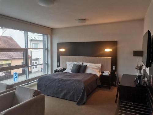 a bedroom with a bed and a large window at Hotel Monde in Uherský Brod